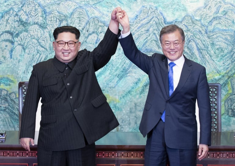 North Korea's leader Kim Jong Un (L) and South Korea's President Moon Jae-in (R) raise their jointed hands during a signing ceremony near the end of their historic summit at the truce village of Panmunjom on April 27, 2018. The leaders of South and North Korea embraced warmly after signing a statement in which they declared "there will be no more war on the Korean Peninsula". / AFP PHOTO / Korea Summit Press Pool / Korea Summit Press Pool