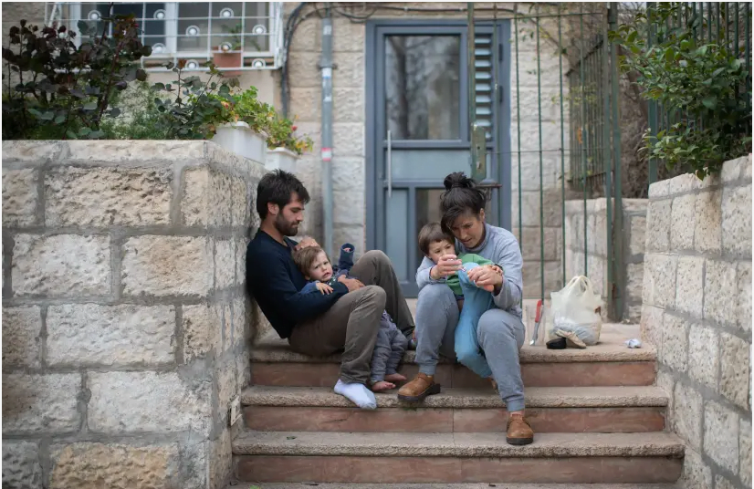 Une famille israélienne est assise sur les marches à l'extérieur de son immeuble à Jérusalem, alors qu'elle reste à la maison avec ses enfants pendant une quarantaine nationale, le 31 mars 2020. (crédit photo: HADAS PARUSH / FLASH90)