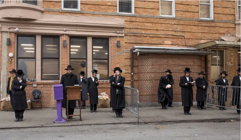 Des hommes hassidiques prient à l'extérieur lors d'un service socialement éloigné dans le quartier de Borough Park à Brooklyn, le 30 mars 2020. (crédit photo: AVI KAYE)