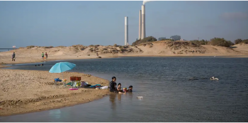Une centrale électrique vue à l'arrière-plan de l'endroit où les Israéliens aiment nager dans un lac au bord de la plage de Zikim, dans le sud d'Israël, près de la frontière avec Gaza le 06 juillet 2015. (crédit photo: MIRIAM ALSTER / FLASH90)
