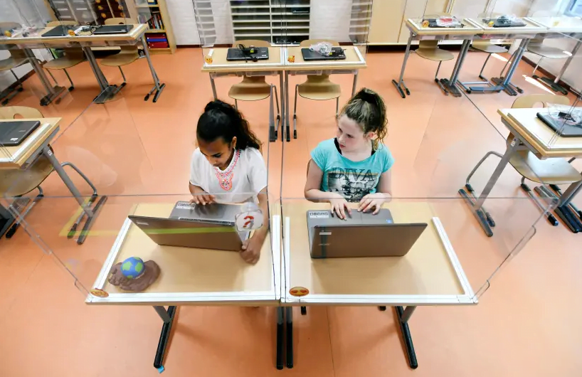 Les élèves assis derrière des cloisons en plexiglas assistent à une classe dans une école primaire (crédit photo: REUTERS)