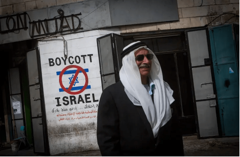 Un Palestinien passe devant un graffiti appelant à boycotter Israël vu dans une rue de Bethléem, en Cisjordanie, le 11 février 2015. (crédit photo: MIRIAM ALSTER / FLASH90)