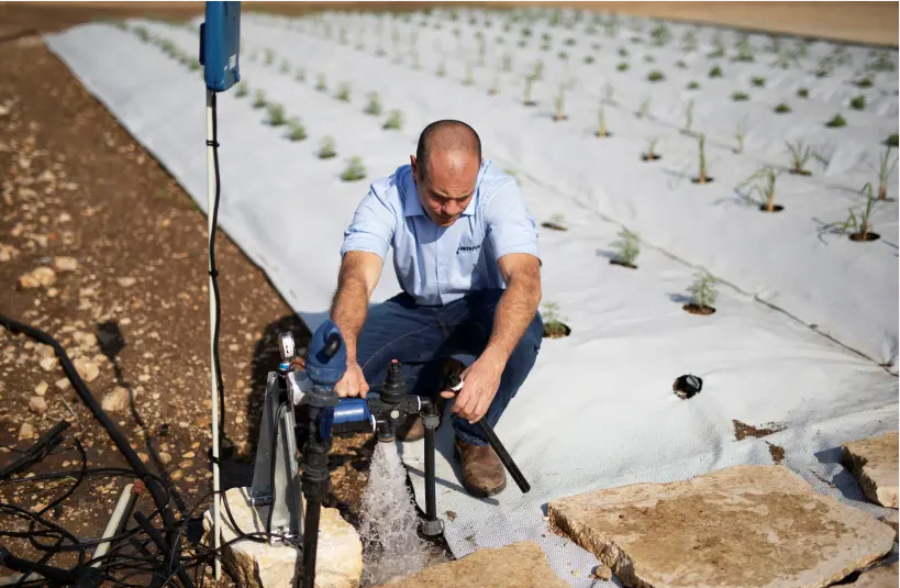 Un employé de Netafim s'agenouille à côté d'un système d'irrigation dans un centre de recherche où l'entreprise développe des méthodes plus efficaces pour arroser les cultures dans le kibboutz Magal, Israël, le 30 novembre 2020. (crédit photo: AMIR COHEN / REUTERS)